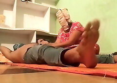 Young Indian woman gives foot massage to a boy in a room with green walls