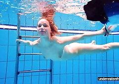 Redhead babe swimming naked in the pool