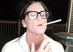 Athletic Female-dominator Kandy stands on her deck at night, smokin' in a constricted white blouse and ebony miniskirt. Glasses on, hair up, heel