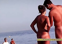 Naked couple is talking on the nudist beach in the middle of the day, while standing