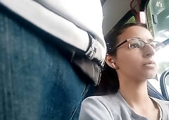 Young Brazilian woman with glasses rests on a bus while being subtly observed