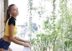 Great looking teen with pretty, blue eyes, Katya Clover is posing in nature's garb on the balcony