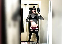 A youthful femboy films himself in the mirror, wanking his clitoris. This guy's wearing red pants, high heels, a mask, and earflaps, teasing his 