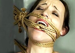 Serf Mila is restrained in Implacable rope servitude, her body wrapped tightly from head to toe. Her legs, belly, tits, neck, and even her throat are 