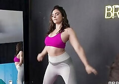 Nina White and Violet Starr stretch in the gym, sweating throughout their sheer garments and glistening with a post-workout glow. Nina White hits the 