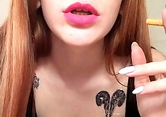 Smoking Redhead With Bright Makeup In A Black Leather Dress